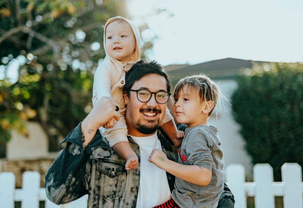 man in white shirt carrying girl in gray shirt