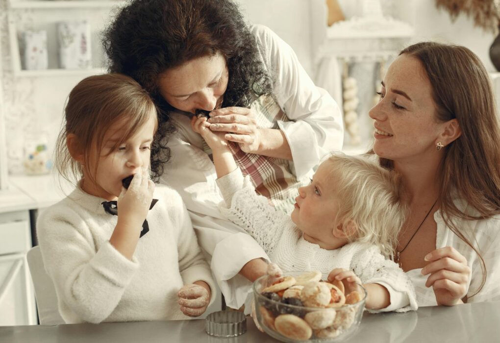Positive Parenting: Build Strong Family Bonds & Child Development Grandmother, mother, and daughters enjoying baking cookies together in cozy kitchen setting.