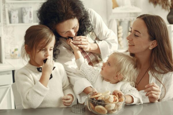 Positive Parenting: Build Strong Family Bonds & Child Development Grandmother, mother, and daughters enjoying baking cookies together in cozy kitchen setting.